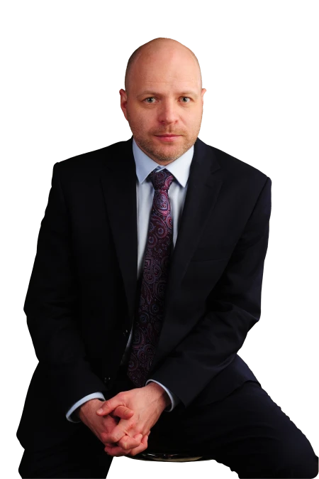 Adwokat Adam Bratkowski, specjalizujący się w sprawach rozwodowych, podziałach majątku i alimentach, siedzący w garniturze na tle neutralnym.